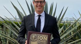 A man in a suit holding an ion fellow plaque.