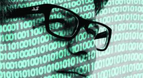 An image of a man with glasses in front of a binary code.